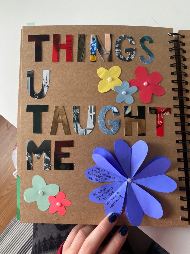 a person holding up a book with paper flowers on it and the words things taught me