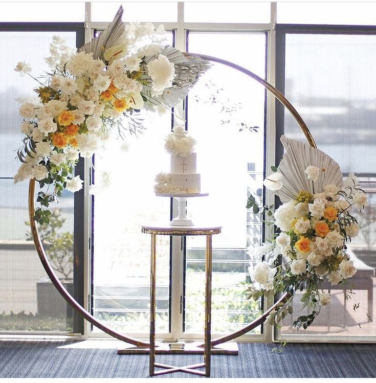 a wedding cake with flowers on it sitting in front of a circular display window at the end of a ceremony