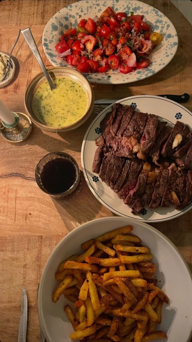 steak, french fries and salad on a wooden table with utensils next to it