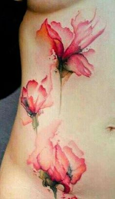 a woman's stomach with pink flowers tattooed on her side and the words watercolor tattoo