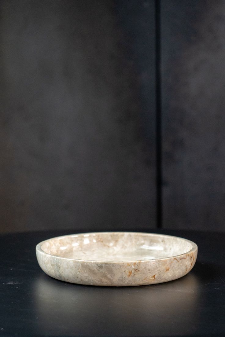 a marble bowl sitting on top of a black table