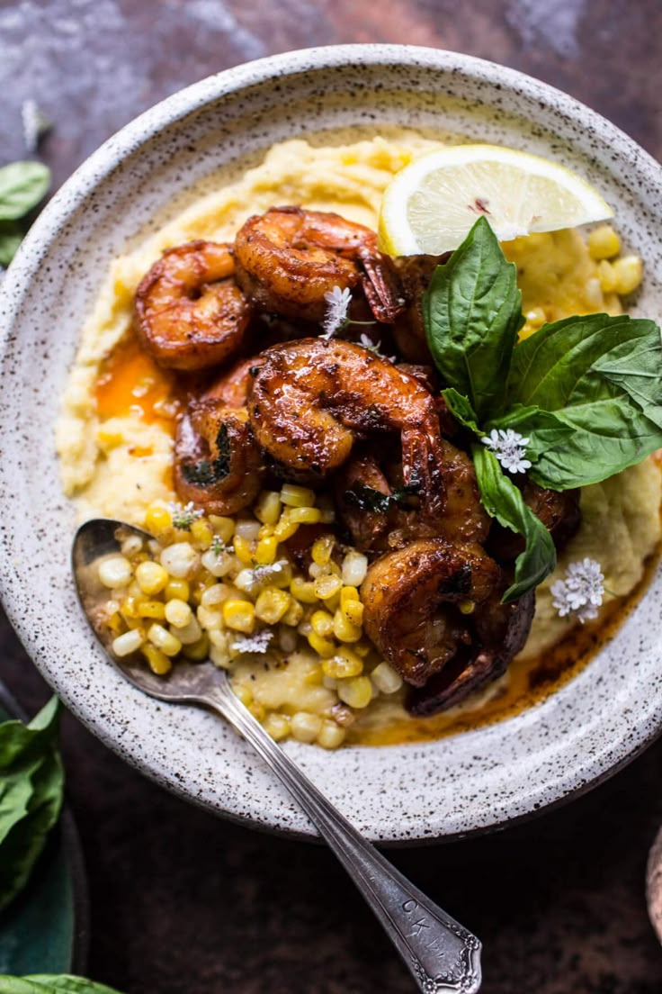 a bowl filled with shrimp and grits on top of a table next to a spoon