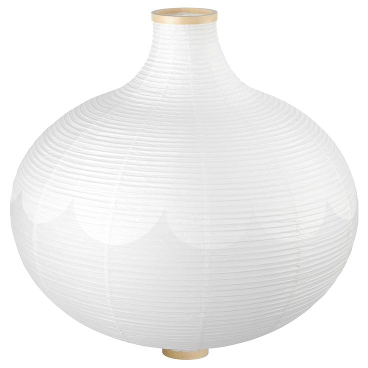 a large white vase sitting on top of a wooden table next to a lamp shade