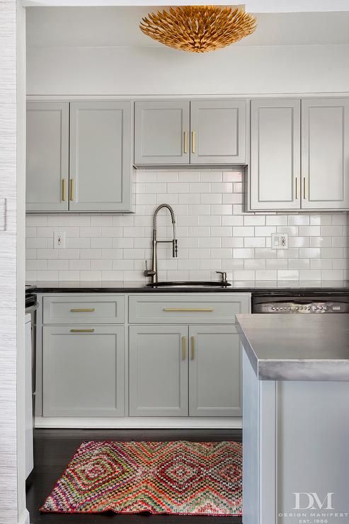 a kitchen with white cabinets and an area rug in front of the stove top oven