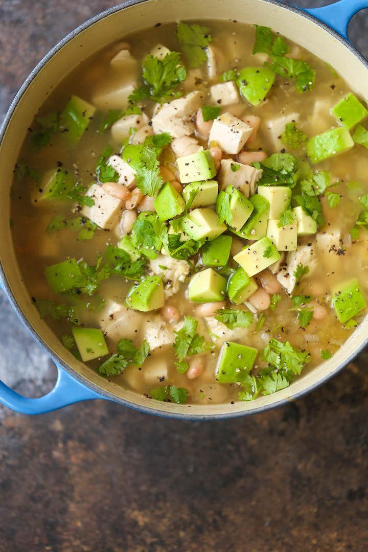 a blue pot filled with chicken and avocado soup on top of a table