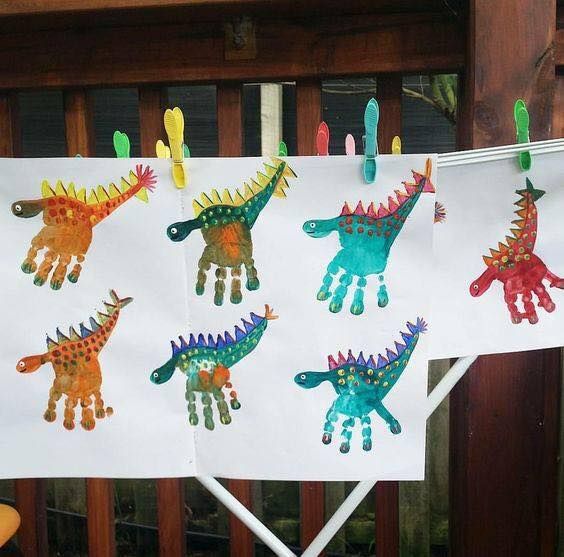 three handprints of dinosaurs hanging on clothesline with pegs in front of them