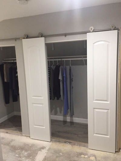 an empty room with two white doors and some clothes hanging on the hooks in it