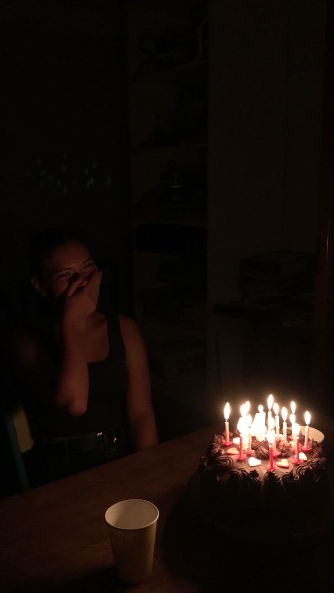 a woman sitting in front of a cake with lit candles