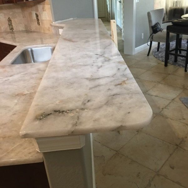 a marble counter top in a kitchen next to a dining room and living room area