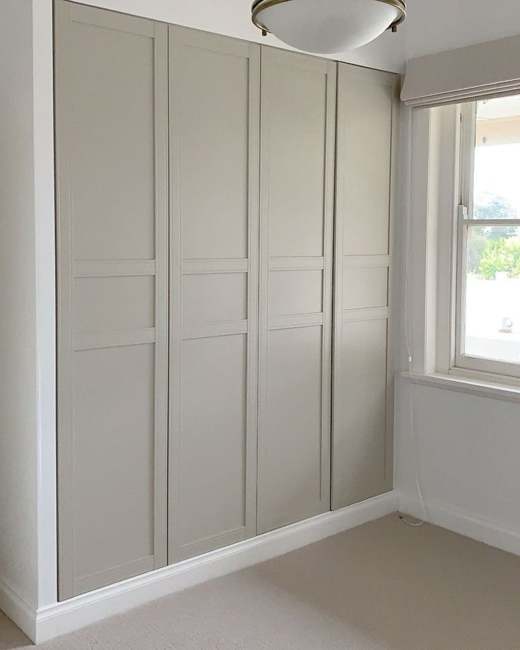 an empty room with white walls and cupboards in the corner, next to a window