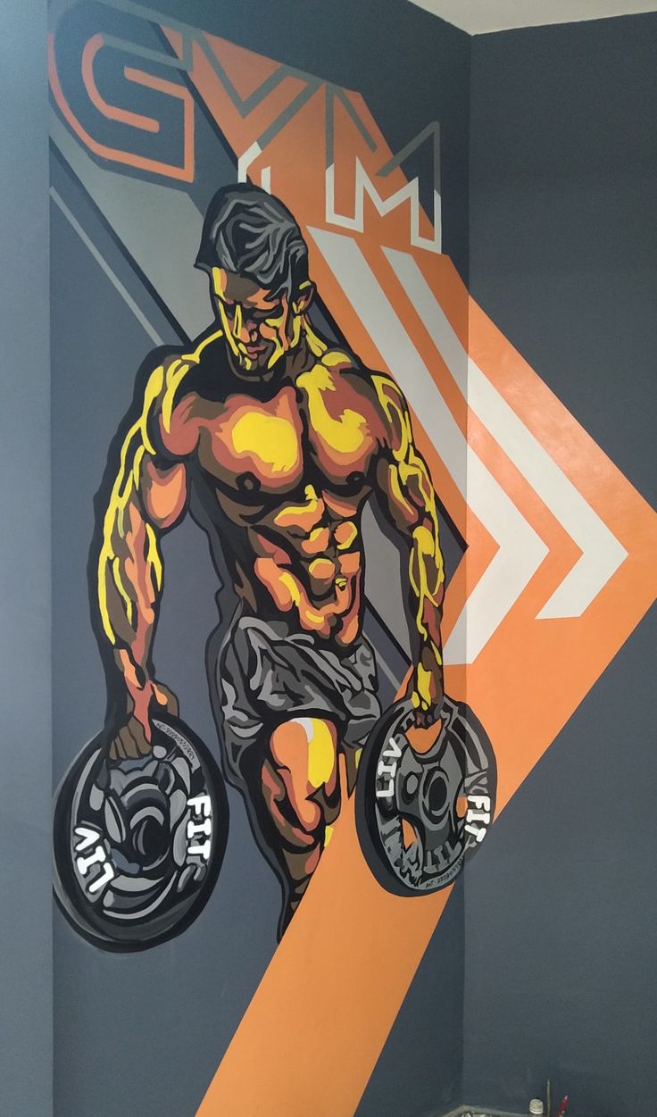 a man is holding two barbells in front of a gym mural on the wall