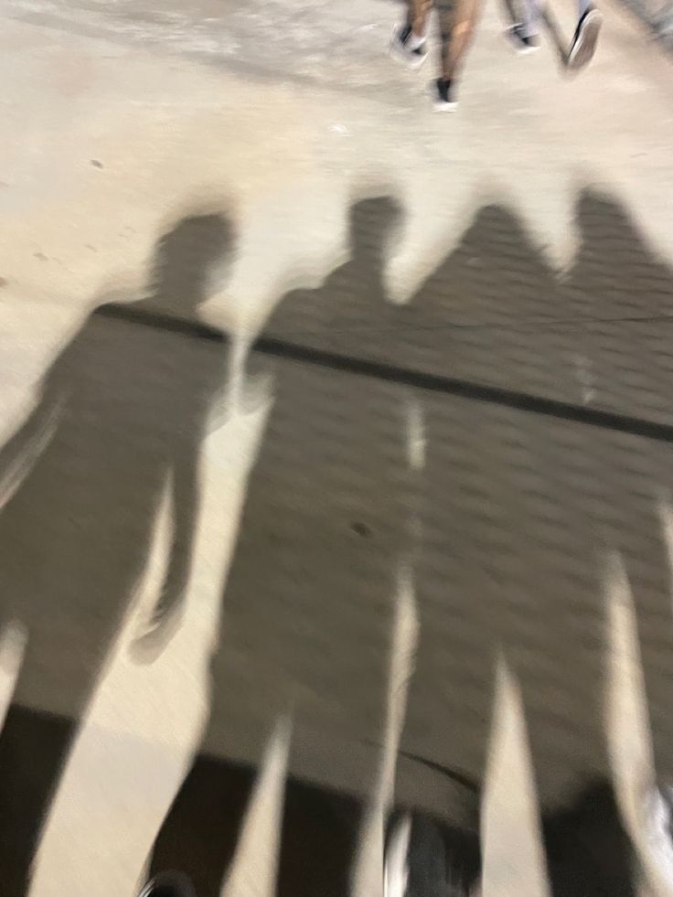 the shadows of people are cast on the ground as they walk down the street with their feet in the air