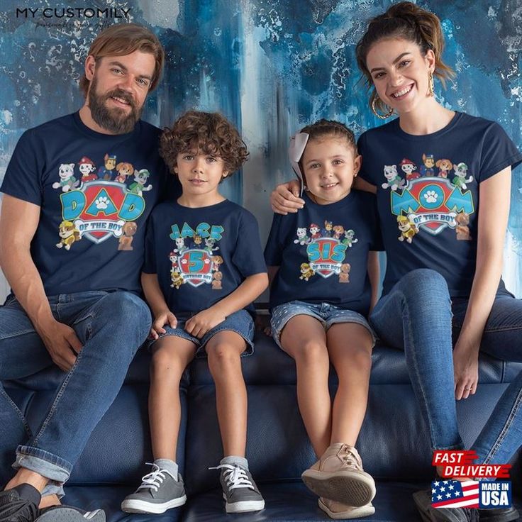 a family wearing matching tshirts sitting on a couch in front of a blue wall