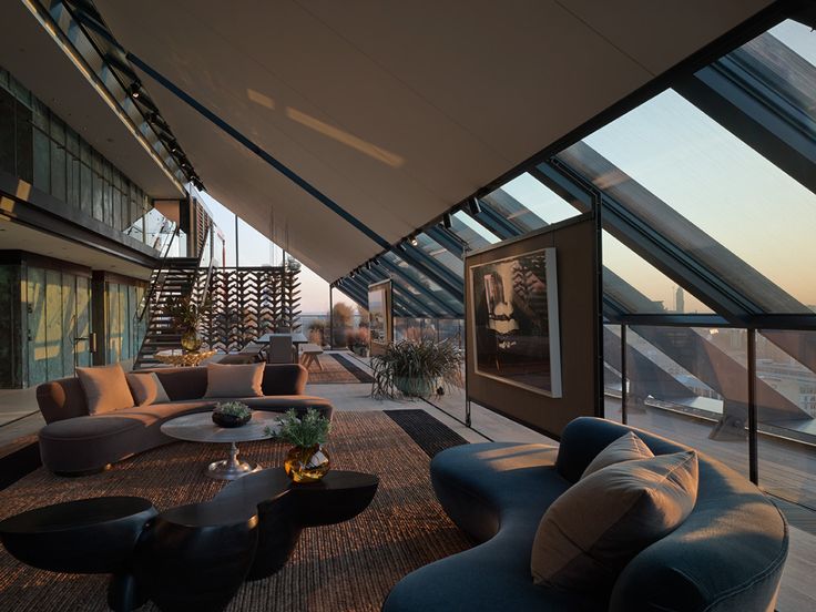 a living room filled with lots of furniture under a glass roof over looking the ocean