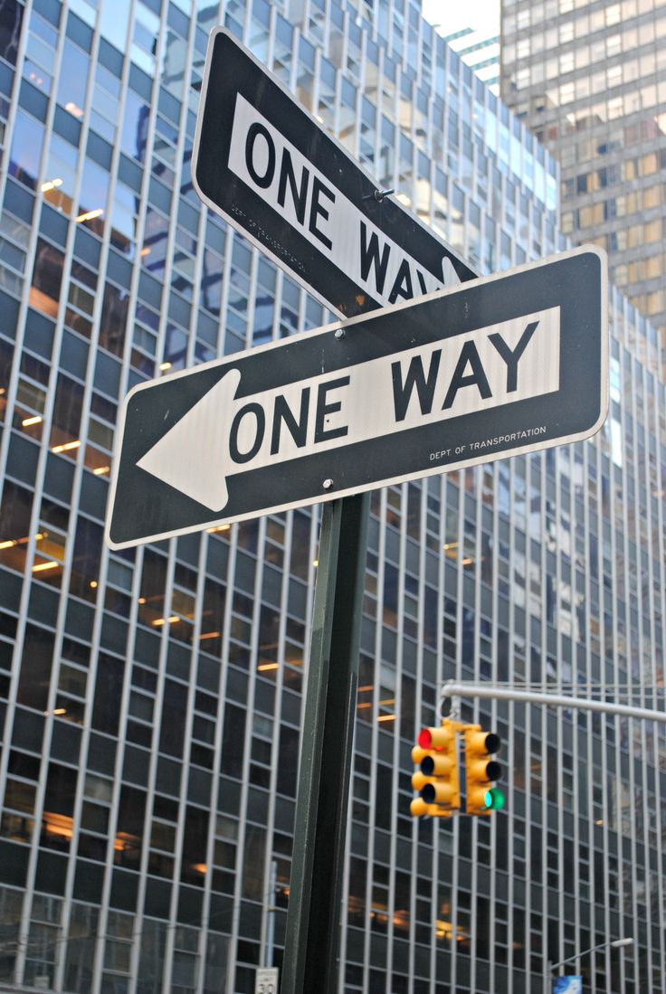 one way and one way street signs in front of tall buildings