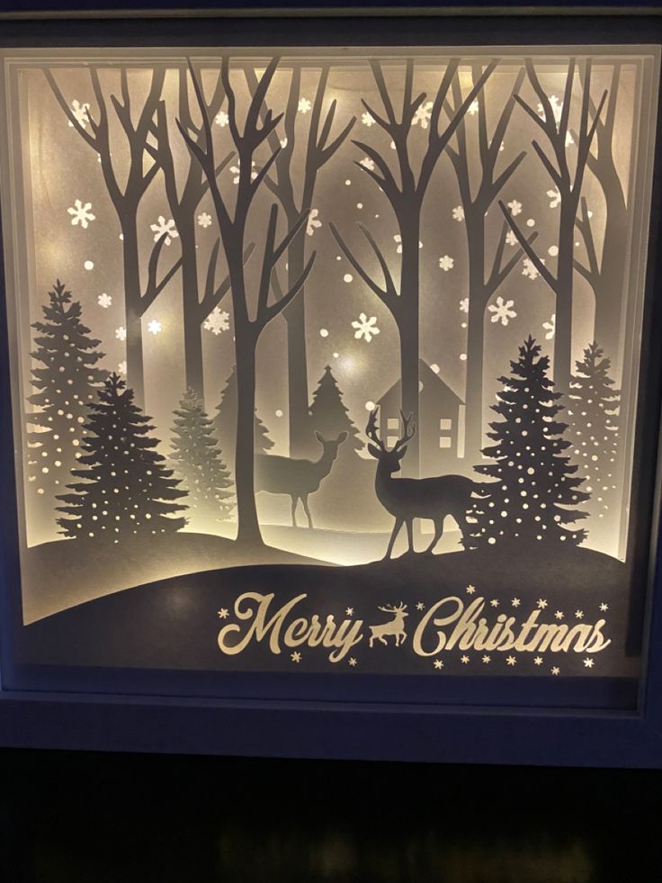 a paper cut christmas scene with deer and trees