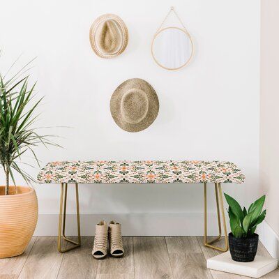 a bench with a hat on it next to a potted plant and two wall hangings