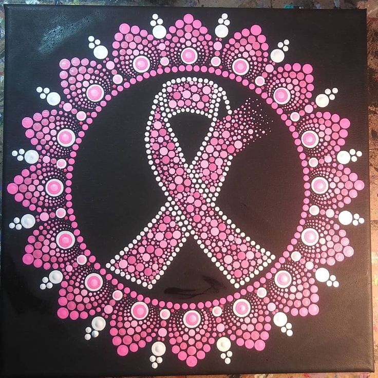 a pink ribbon is in the middle of a circle made out of circles and dots