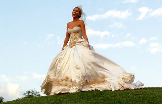 a woman in a wedding dress standing on top of a hill