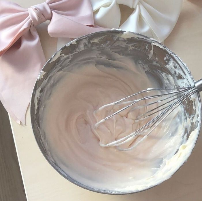 a metal bowl filled with batter next to a pink bow