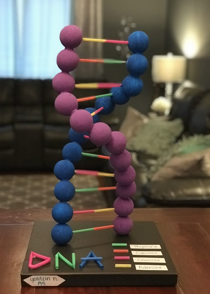 a wooden table topped with a purple and blue bead sculpture next to a couch