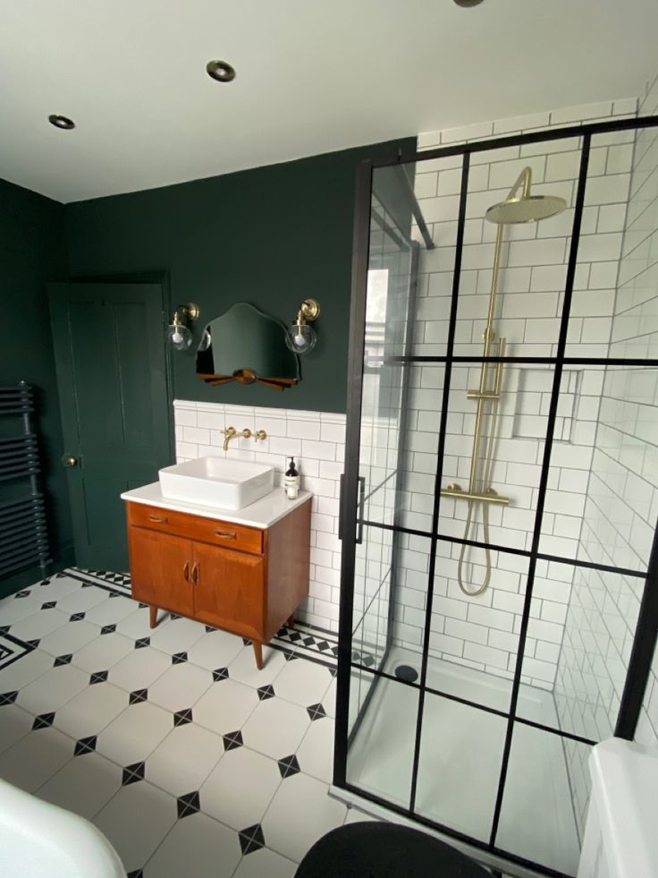 a bathroom with black and white tile flooring, green walls and a shower stall