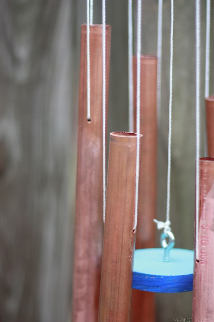 a wind chime hanging from the side of a wooden fence next to tall poles