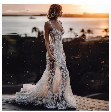 a woman in a white dress standing on a wooden deck next to the ocean at sunset