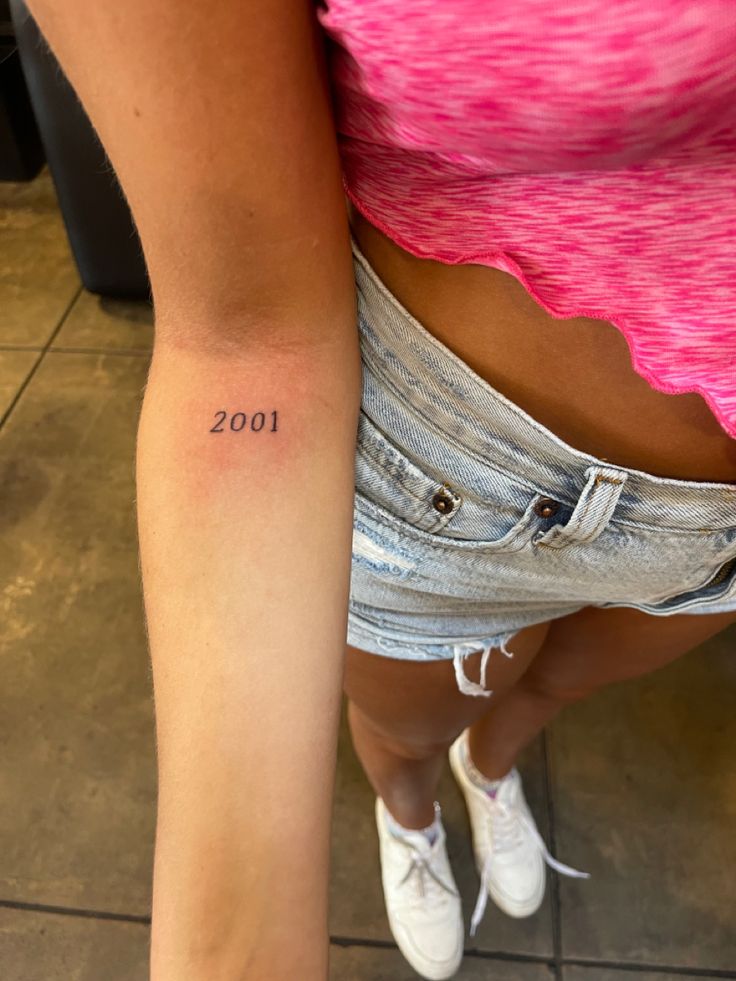 a woman with a small tattoo on her left arm and the number 2000 written in it