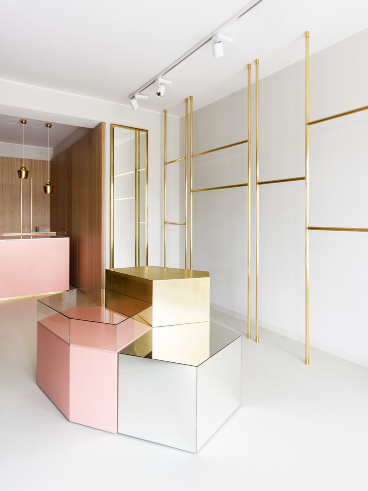 three different colored boxes in a room with gold and pink accents on the wall behind them