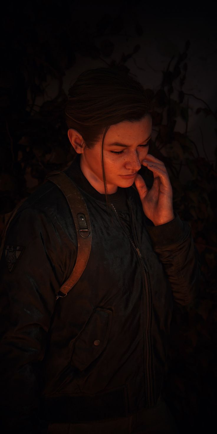 a young man is talking on his cell phone in the dark while wearing a leather jacket