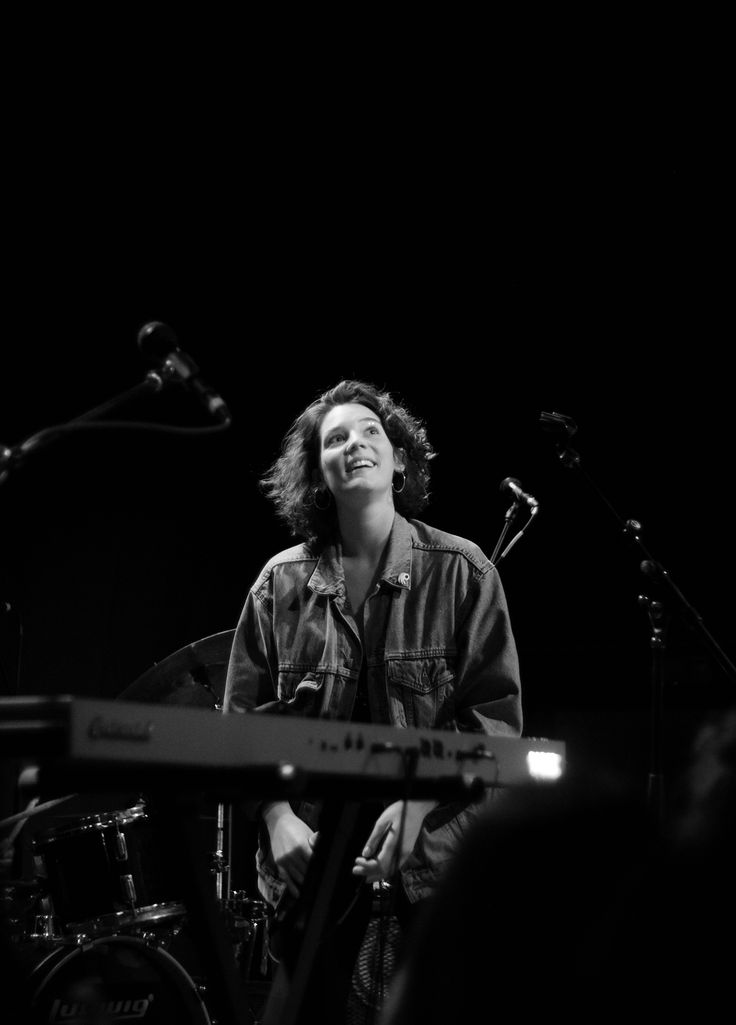 a black and white photo of a man playing the guitar in front of microphones