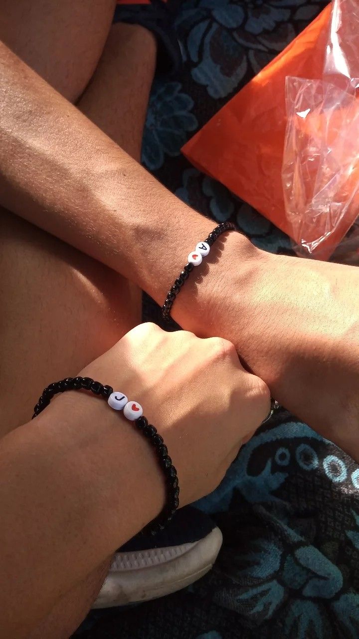 two people wearing bracelets sitting next to each other