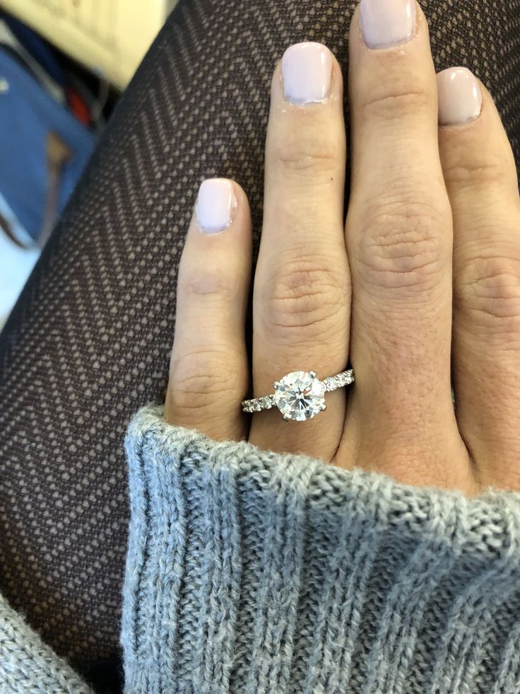 a woman's hand with a diamond ring on her finger, sitting in a chair