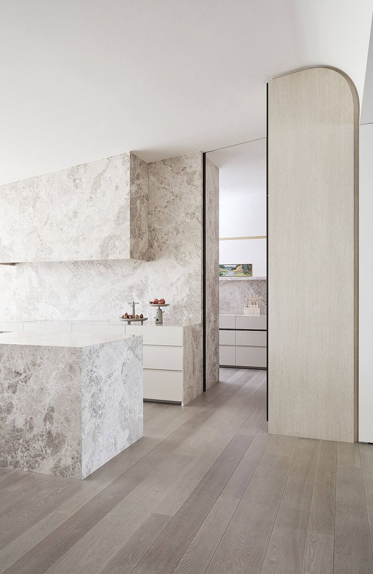 a large white kitchen with marble counter tops and an island in front of the sink