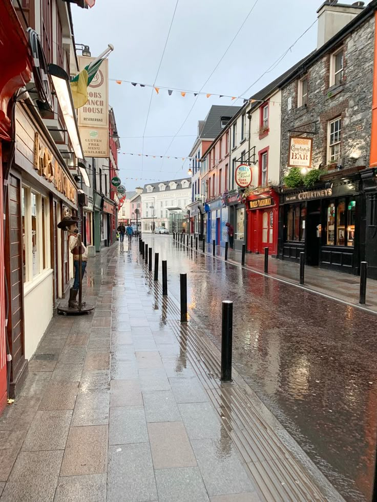 a wet street with shops and people walking on it