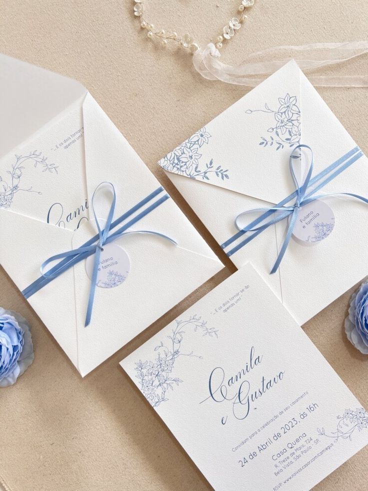 the wedding stationery is laid out on top of the table with blue flowers and ribbons