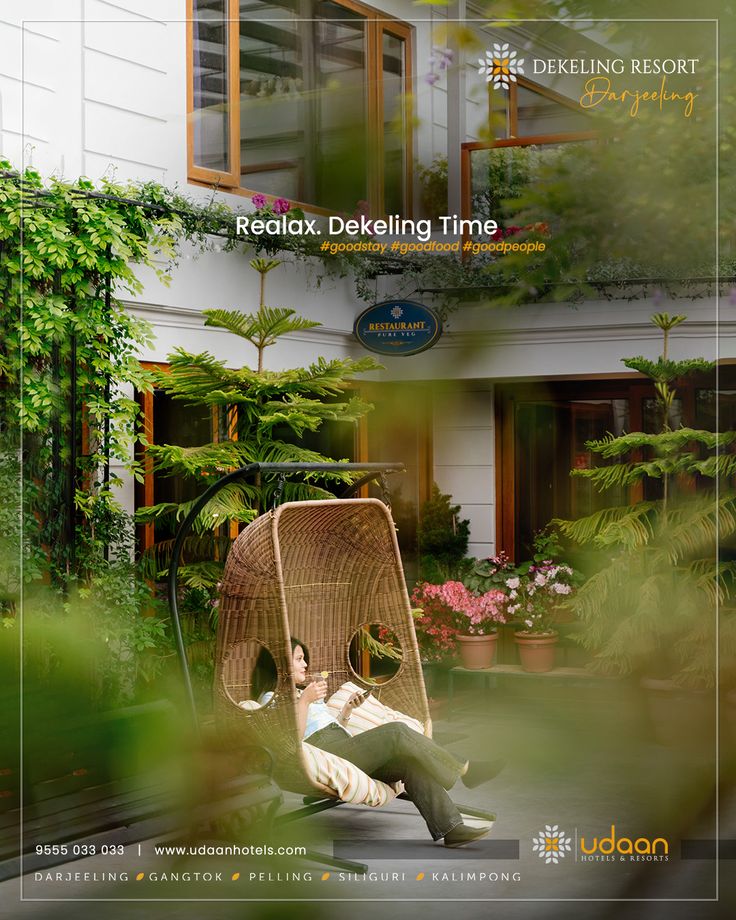 a man is sitting in a chair with plants on the outside and behind him there is an advertisement for a hotel