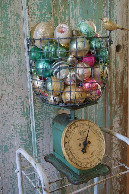 an old fashioned kitchen scale with ornaments in the basket on it's top shelf