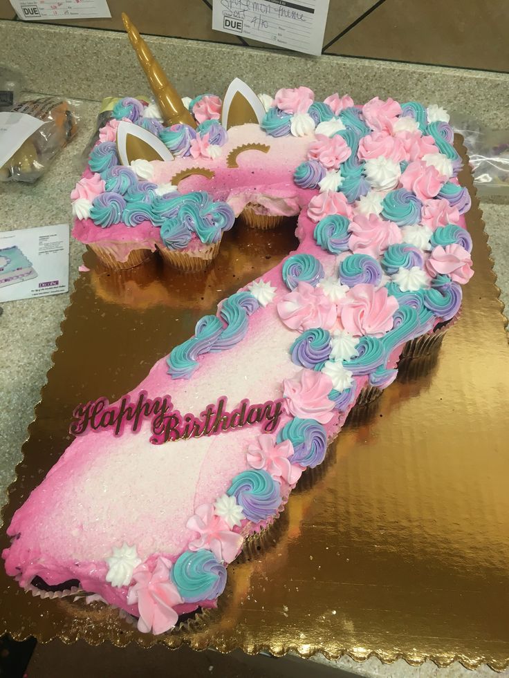 a pink and blue birthday cake that is shaped like the number seven with flowers on it