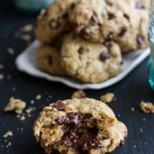 chocolate chip cookies with crumbs on a table next to a glass of water