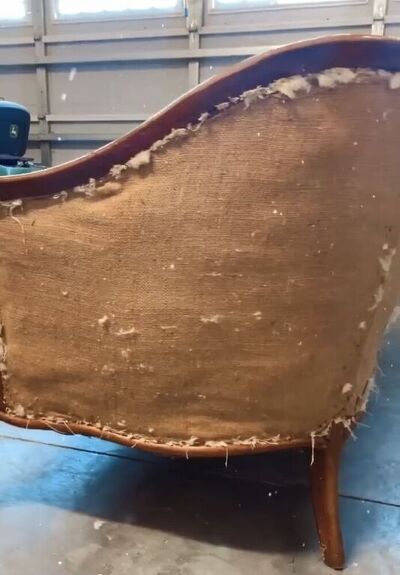 an old chair that has been upholstered and is sitting on the floor in a garage