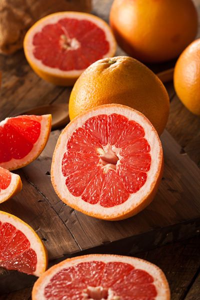 grapefruits cut in half on a cutting board with other fruits around them