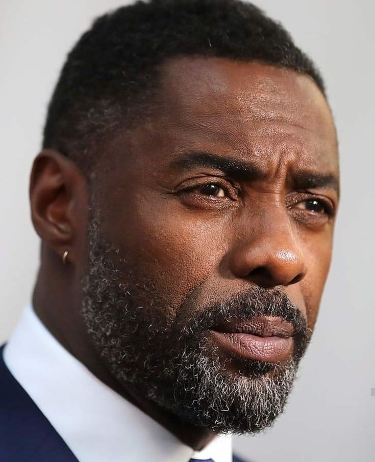 a close up of a person wearing a suit and tie with a serious look on his face