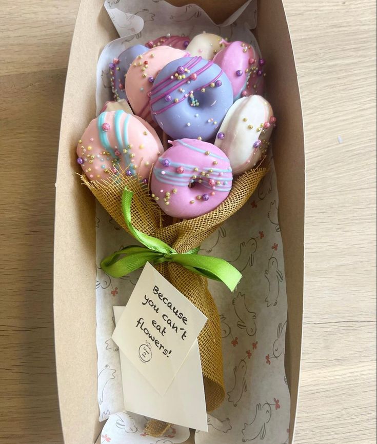 a box filled with donuts covered in sprinkles next to a note