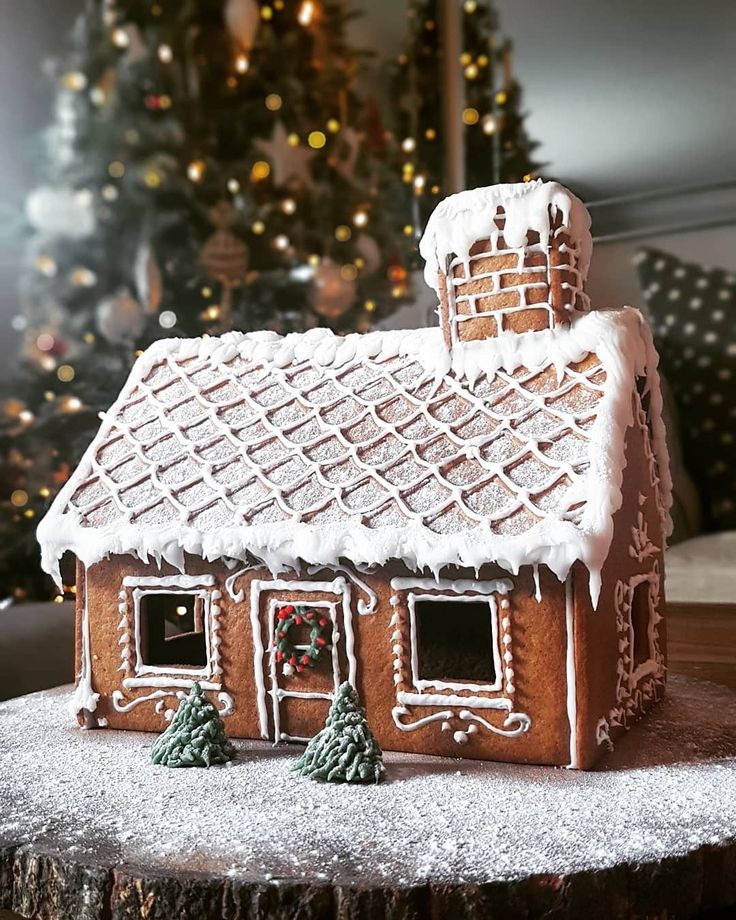 a gingerbread house on a table with a christmas tree in the background