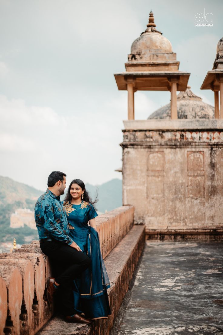 a man and woman are sitting on a wall