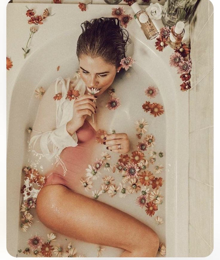 a woman in a bathtub with flowers around her