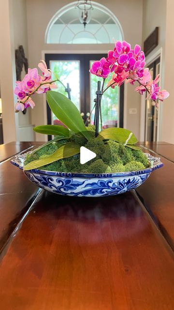 a blue and white bowl with pink flowers in it