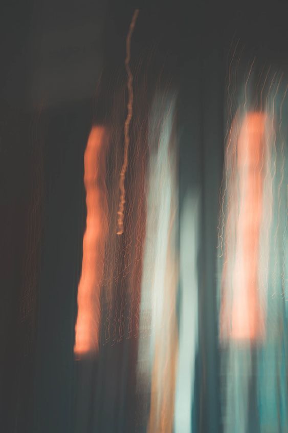 blurry photograph of trees in front of a window with orange light coming from them